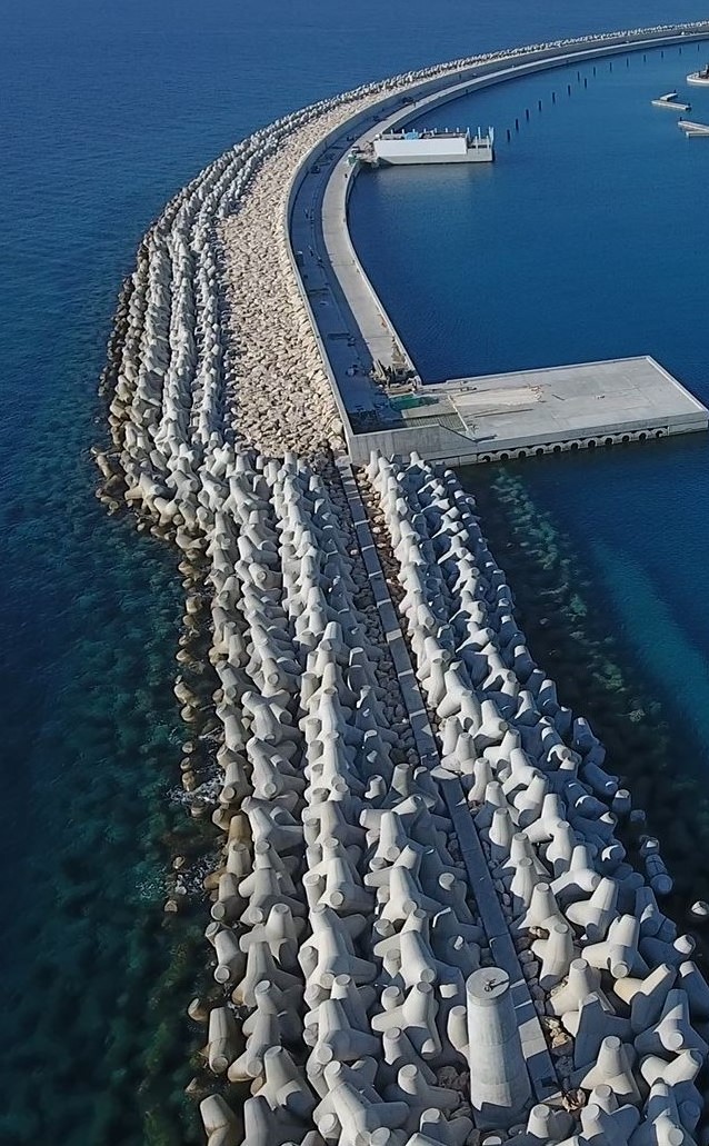 Aerial view of a curved armored breakwater lined with concrete armor units